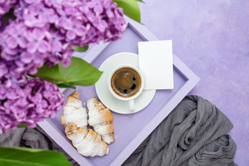 Obraz na płótnie Canvas Breakfast. A lilac tray with a cup of coffee and bagels (croissants) and a card for text and an awesome sprig of lilacs.