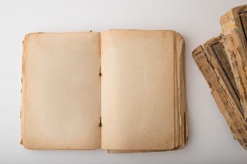 An old opened book with yellowed pages without text near to another two ancient volumes. Concept image of gaining knowledge.
