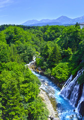 Fototapeta na wymiar 初夏の北海道、美瑛町にある白髭の滝と十勝岳連峰