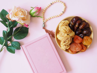Sweets, dates, dried apricots on a plate on a pinkbackground. Flower. The concept of Ramadan, iftar..