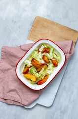salad with greens and baked peach on marble background with copy space