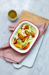 salad with greens and baked peach on marble background with copy space