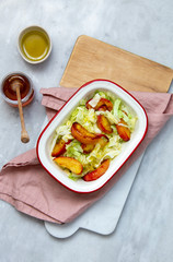 salad with greens and baked peach on marble background with copy space