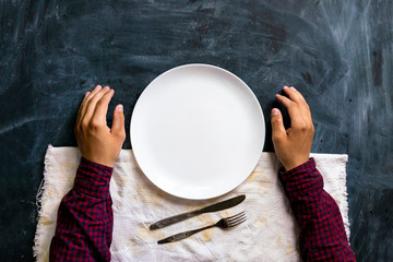 top view of person's hands on the table with empty plate design mock up designs
