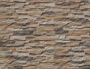 Stone wall cladding made of stripes artificial rocks. The colors are black,brown and gray...