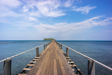 Obraz premium Wood bridge stands into the sea with blue sky