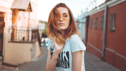 Fashion portrait stylish pretty woman in sunglasses posing in the city, street fashion. Sunny light