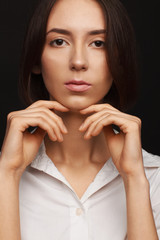 Portrait of a beautiful pacified woman in a white shirt on a light background
