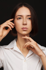 Portrait of a beautiful pacified woman in a white shirt on a light background