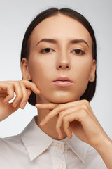 Portrait of a beautiful pacified woman in a white shirt on a light background