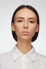 Portrait of a beautiful pacified woman in a white shirt on a light background