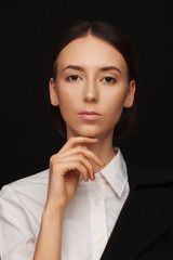 Portrait of a beautiful pacified woman in a white shirt and black jacket. Studio photo session