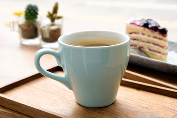 Hot coffee with a blueberry cake in a wooden tray
