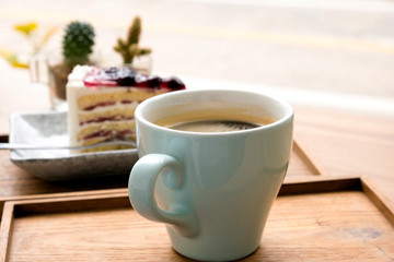 Hot coffee with a blueberry cake in a wooden tray