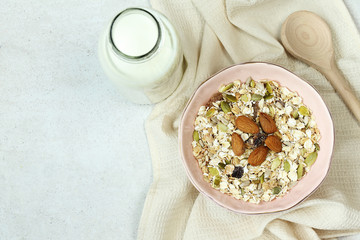 Plate with muesli, bottle of milk and wooden spoon on grey concrete background