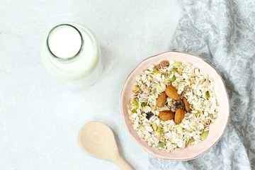 Muesli, bottle of milk and wooden spoon on grey towel