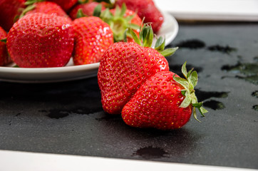strawberries in a white plate on a black background