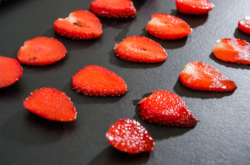Delicious strawberries, cut into slices on a black background. Background with strawberries.