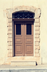 The background old beige stony wall with retro door