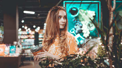 Young woman buying flowers in a pot at a garden center