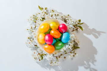 Plate with Easter eggs and spring flowers on a light background. Easter celebration concept