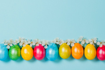Easter eggs and spring flowers on a blue background. Concept of celebrating Easter. Flat lay, top view