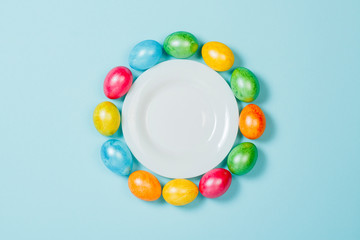 Easter eggs on a plate on a blue background. Concept of celebrating Easter. Flat lay, top view