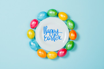 Easter eggs on a plate on a blue background. Concept of celebrating Easter. Flat lay, top view