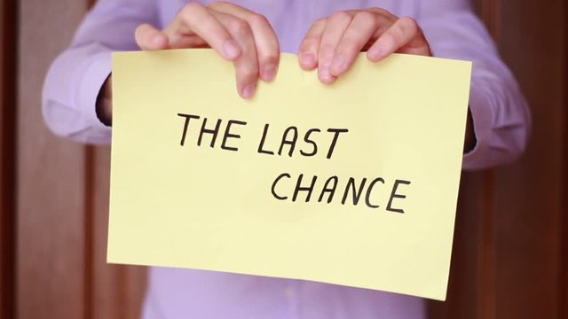 Ripping up yellow sheet with "The last chance" inscription