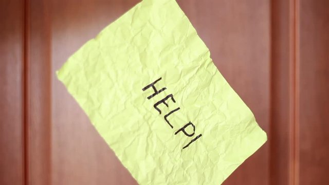 "Help" inscription on rumpled yellow sheet of paper