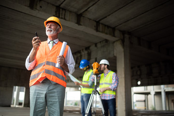 Engineer and construction site manager dealing with blueprints and plans