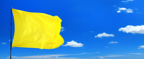 Conceptual image of waving blank yellow flag over sunny blue sky