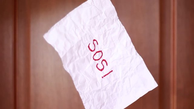 Suspended "SOS" inscription on rumpled sheet