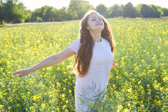 The girl in the field with flowers and pollen breathes deeply, happy about the lack of allergy