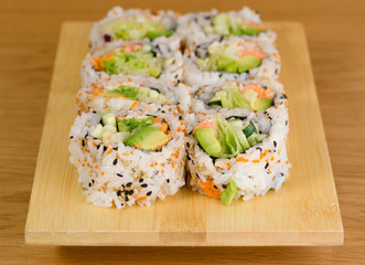 sushi roll with zucchini, crab meat, salad, avocado and carrots, covered with caviar, black and white sesame