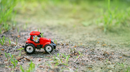 red tractor model and white meadow flowers on blurred natural background. summer season, agriculture, farming, garden. copy space. 