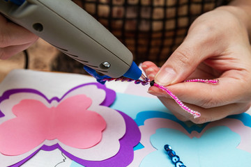 Woman uses hot melt glue gun in handmade applications. Closeup, selective focus