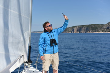 Man sailing with sails out on a sunny day and making selfie