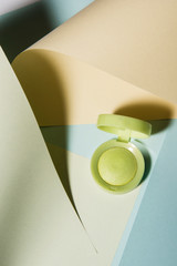 Professional makeup, green eye shadow powder with colorful curves paper background. Abstract conception.