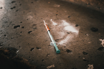 Heroin syringe on rough concrete, dirty background