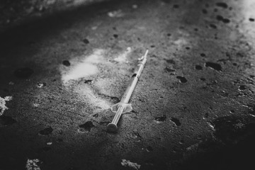 Heroin syringe on rough concrete, dirty background