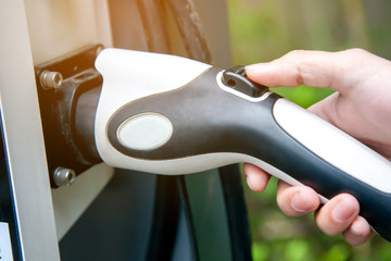 Man hand holding electric plug for charging electric car.