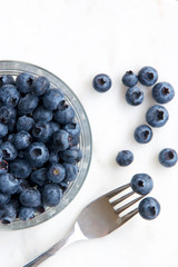 Blueberries on a glass dish with a spoon.