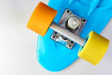 Detail of blue plastic mini cruiser penny board or skate board with yellow and orange wheels and...