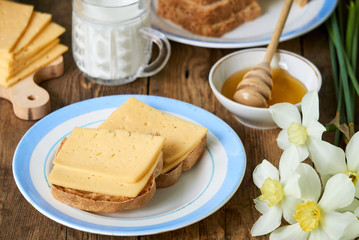 Breakfast with cheese sandwich, milk and honey on a wooden table