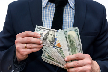 Man in suit holding pile of dollar banknotes
