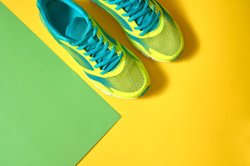 Pair of sport running shoes on colorful background. New sneakers on green and yellow pastel...