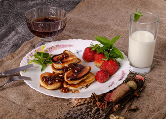 Pancakes with strawberry jam and ripe strawberries and milk