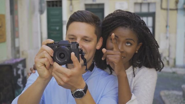 Couple of tourists taking pictures of sightseeings. Smiling African American woman pointing while her Caucasian boyfriend photographing. Photography concept