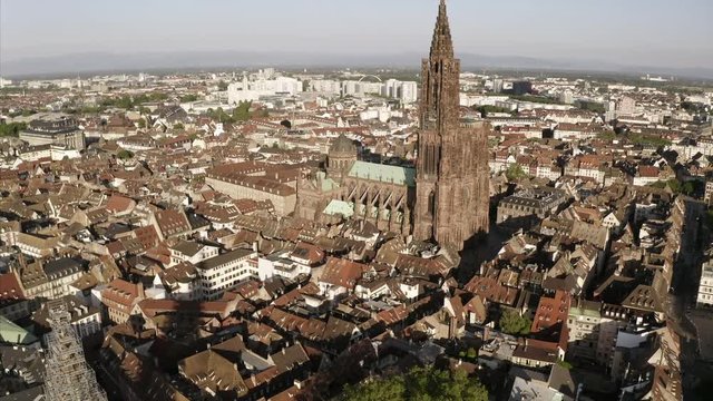 The Notre Dame de Strasbourg in an aerial shot. The drone is circeling around the towers of the cathedral. The central cityscape can be seen from above.
